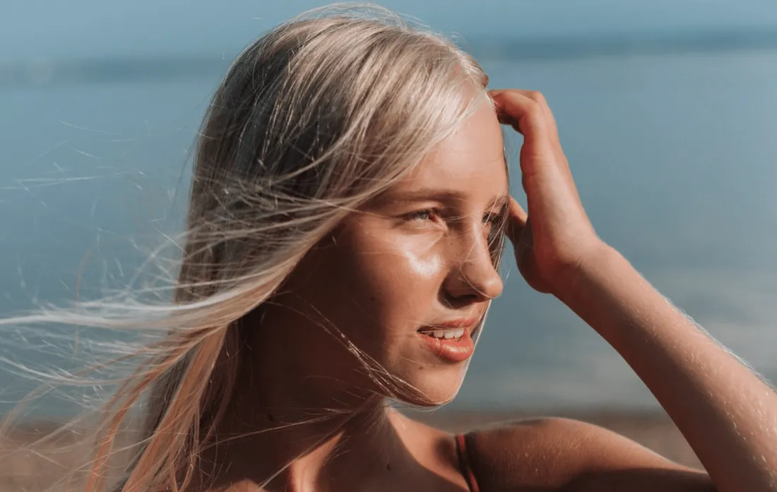 Woman with windblown blonde hair by the ocean