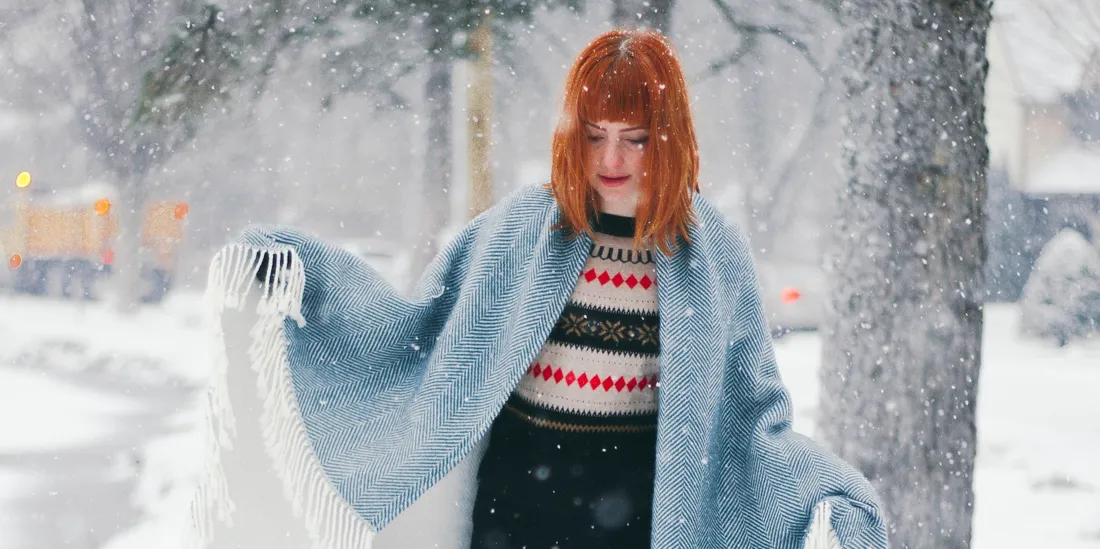 Person with copper-red hair standing in falling snow